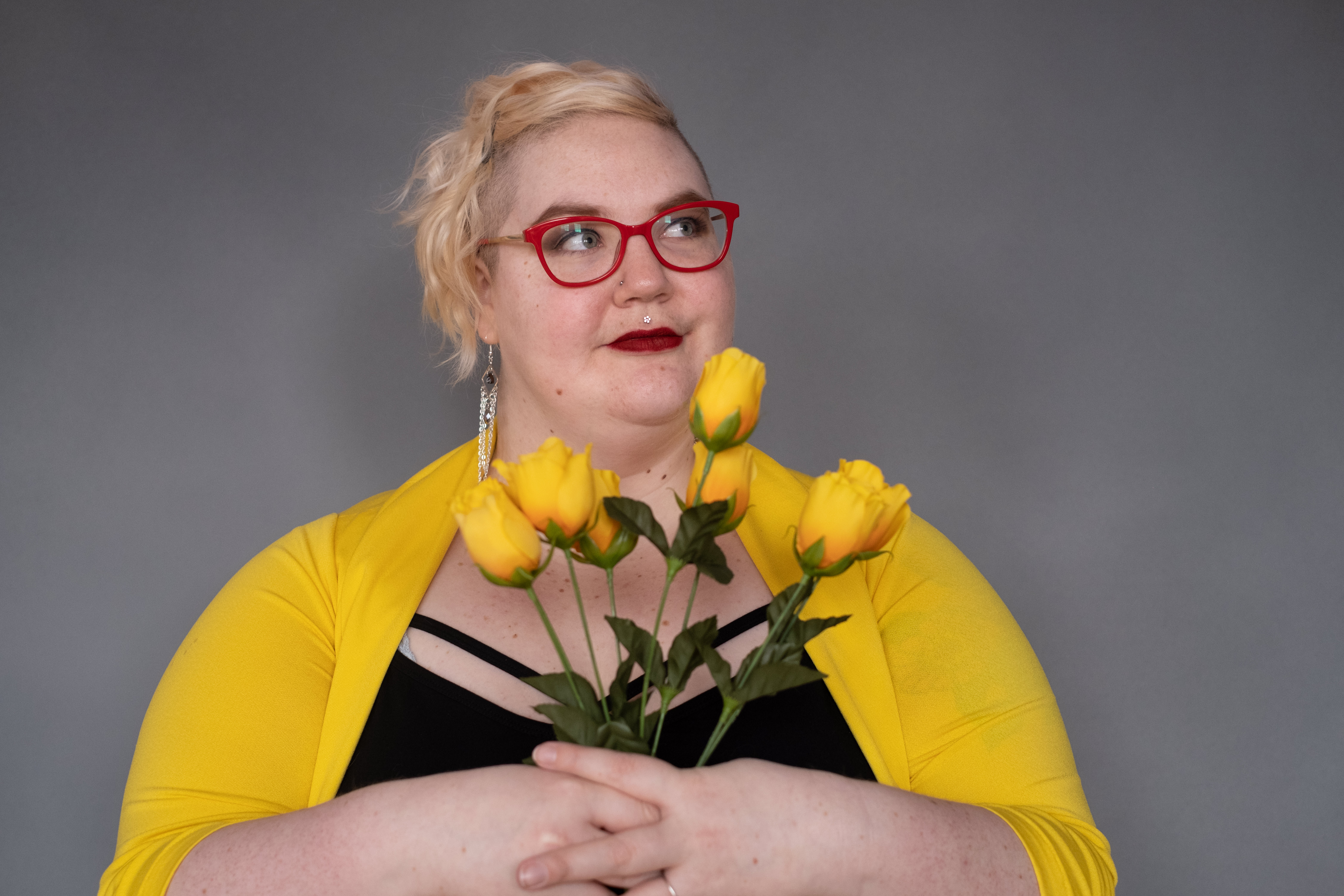 Caitlin is looking off camera while holding a bouquet of yellow tulips.